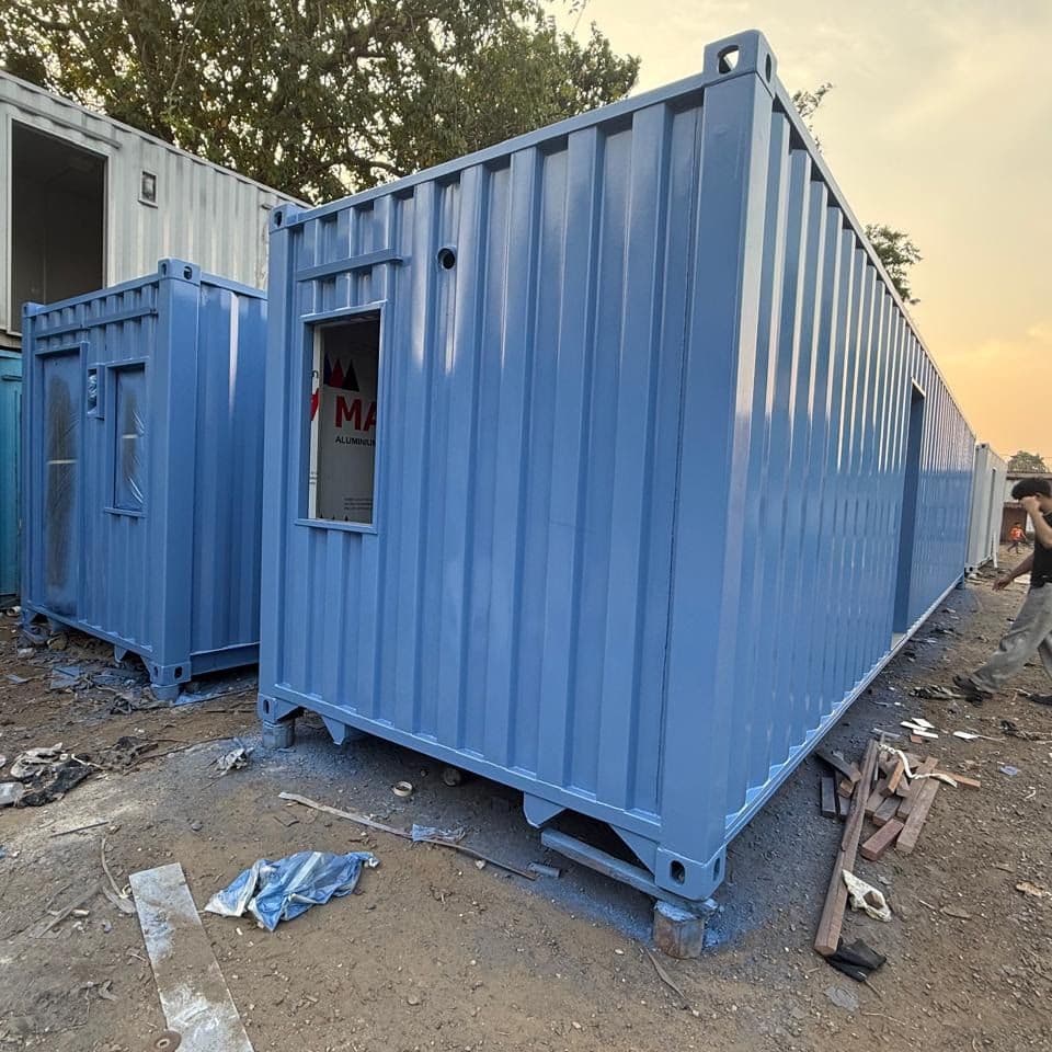 Dua unit container biru berdampingan dengan pintu dan jendela kecil